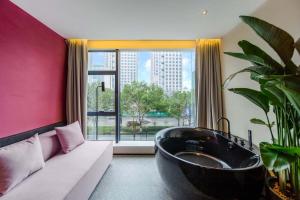 a bathroom with a black tub in a room with a couch at M Hotel in Hangzhou