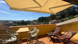 a patio with chairs and a table and an umbrella at Casa Eira de Arriba - by entreRías in Cangas de Morrazo