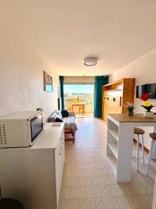 a kitchen and living room with a microwave on a counter at Studio 100m de la mer et port in Valras-Plage