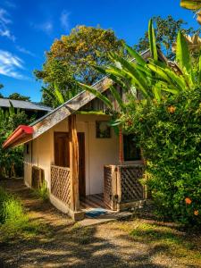 a small white house with a wooden porch at Ballena Oasis Homes & Glamping in Uvita