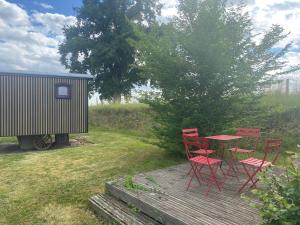 a table and chairs on a deck next to a shed at La Roulotte au Paradis in Arc-et-Senans