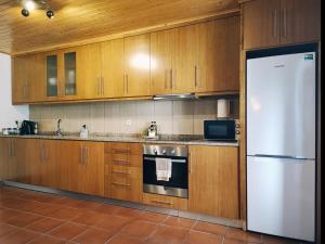 a kitchen with wooden cabinets and a white refrigerator at Casa dos Côtos. in Castro Laboreiro
