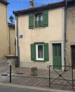 a building with green shutters and a window at La Casa de Nona in Carcassonne