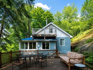 a house with a deck with a table and chairs at Serenity Tree house on the lake in Huberdeau