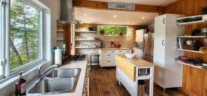 a kitchen with a sink and a refrigerator at Serenity Tree house on the lake in Huberdeau