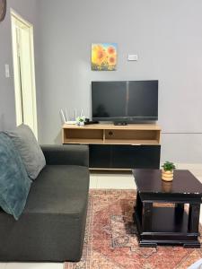a living room with a couch and a flat screen tv at Ekukhanyeni Guest house in Kwaluseni