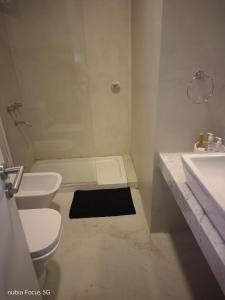 a white bathroom with a toilet and a sink at Monoambiente céntrico Sara in Gualeguaychú +5 photos