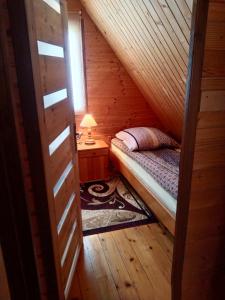 a small bedroom with a bed in a wooden cabin at Agroturystyka Pod Bocianami Terka in Polańczyk