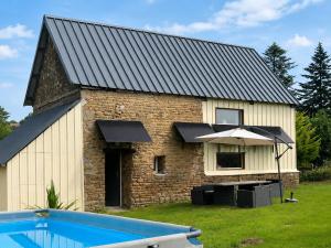 a stone building with an umbrella next to a pool at gite "La Renaudaie" - piscine in Juvigny-le-Tertre