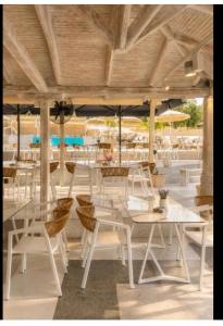 a restaurant with white tables and chairs and umbrellas at Studios Apartments Irini Patira in Potos