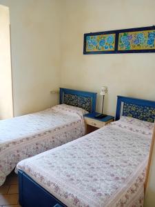 a bedroom with two beds and a table with a lamp at La Casa dei Nonni in Berceto
