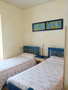 two beds in a room with blue and white sheets at La Casa dei Nonni in Berceto