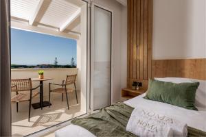 a bedroom with a bed and a balcony with a table at Noma Vasilikos in Vasilikos