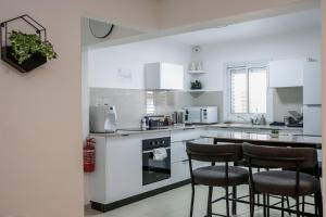 a kitchen with white cabinets and bar stools at Ramon Palms in Mitzpe Ramon