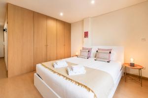 a bedroom with a large white bed with wooden cabinets at GuestReady - MusicHall in Porto