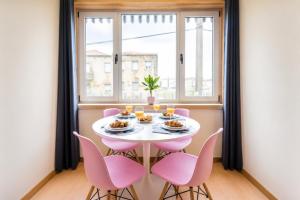 a table with pink chairs in a room with a window at GuestReady - MusicHall in Porto