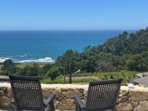 two chairs sitting on a stone wall with the ocean at Holibai Mirada do Roxo 3 suites y vistas al mar in Oia