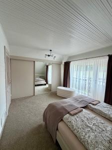a white bedroom with a large bed and a window at Zidinio Liepsnele in Palanga