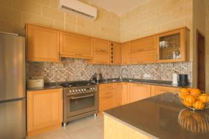 a kitchen with wooden cabinets and a counter top at Villa Joanna in Xagħra
