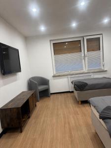ein Zimmer mit zwei Betten, einem Tisch und einem Fernseher in der Unterkunft WeserZeit Apartment in Bodenwerder