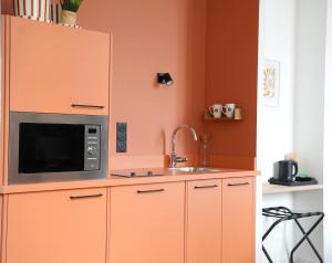 a kitchen with a microwave and a sink at ARBELLIA Appart'Hôtel Châlons en Champagne in Chalons en Champagne