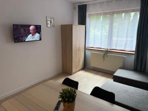 a living room with a table and a tv on the wall at Apartament Tczew-duże pokoje! in Tczew