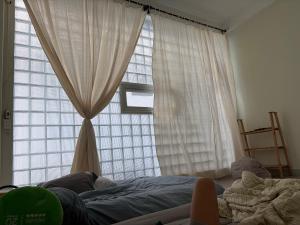 a bedroom with a large window with curtains and a bed at Anhbnb in Danang
