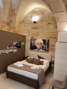 a bedroom with a bed in a stone wall at AvVolta nel Salento - Room & Relax in Torchiarolo