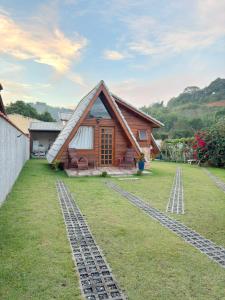 a house with a thatched roof and a grass yard at Chalé Nina in Areias
