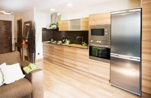 a kitchen with a stainless steel refrigerator and wooden cabinets at Apartaments Petit Saüc in Taüll