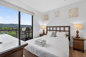 a bedroom with a bed and a large window at Playa Del Sol 2 Bdrm 649 w/ Mountain Views! in Kelowna +20 photos