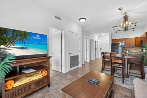 a living room with a large tv and a table at Playa Del Sol 2 Bdrm 649 w/ Mountain Views! in Kelowna