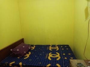 a small room with a bed with yellow walls and yellow at Wahid Homestay in Ketapang