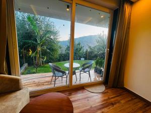a room with a large glass window with a table and chairs at Hotel Casa Del Sol Near'Bhimtal Lake in Bhīm Tāl