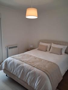 a bedroom with a large bed with a light above it at Casa D'Avó 1 in Trancoso