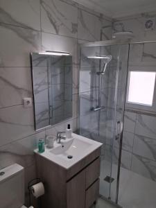 a bathroom with a sink and a shower with a mirror at Casa D'Avó 1 in Trancoso