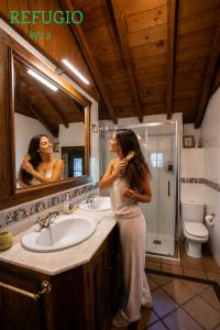 a woman standing in front of a bathroom mirror at Casa rural Paraje de Yuste in Cuacos de Yuste