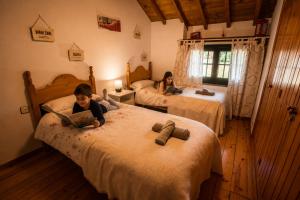a young boy sitting on a bed with a laptop at Casa rural Paraje de Yuste in Cuacos de Yuste