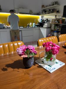 a wooden table with two vases of pink flowers on it at Anhbnb in Danang