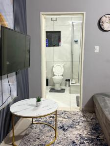 a bathroom with a toilet and a table and a tv at Ekukhanyeni Guest house in Kwaluseni +48 photos