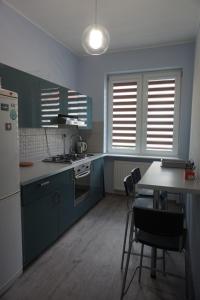 a kitchen with blue cabinets and a table with chairs at Baltic Rooms Gdańsk in Skorka
