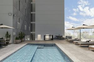 a pool in a building with chairs and umbrellas at Courtyard by Marriott Torreón in Torreón