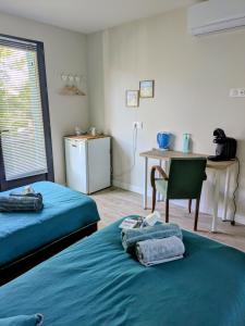 a room with two beds and a table and a desk at Les Pignottes in Gujan-Mestras