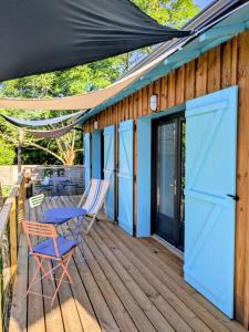 a deck with blue doors and chairs and a table at Les Pignottes in Gujan-Mestras