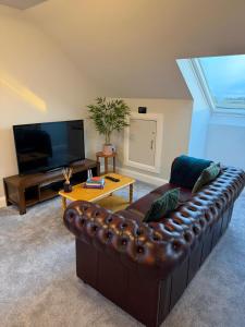 a living room with a brown leather couch and a tv at Homestay Wild Atlantic View Binghamstown in Belmullet