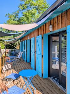 a deck with blue doors and chairs and tables at Les Pignottes in Gujan-Mestras