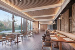 a restaurant with wooden tables and chairs and large windows at Beijing Marriott Hotel Yanqing in Yanqing
