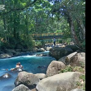 people swimming in a river with a bridge in the background at Bosque celeste in Rio Celeste +11 photos