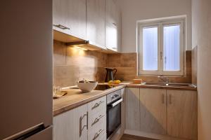 a kitchen with wooden cabinets and a sink and a window at Milesian Suites in Adamantas