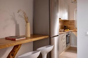 a kitchen with a stainless steel refrigerator and two white stools at Milesian Suites in Adamantas